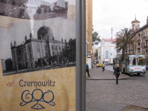 Ein Werbefoto mit der Synagoge. Im Hintergrund, hellblau, das gleiche Gebäude heute: ein Kino.